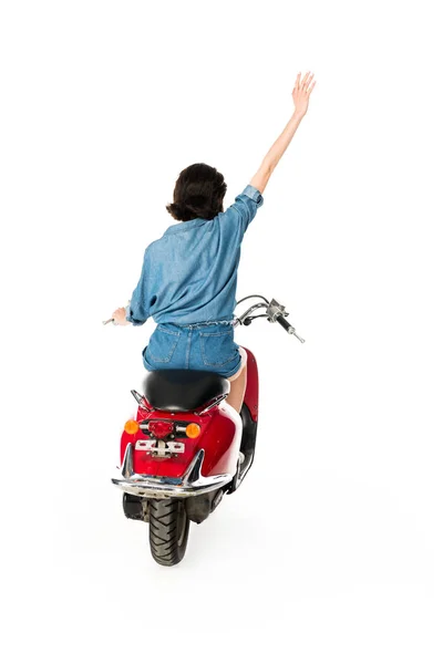 Вид сзади девушки с рукой в воздухе, сидящей на красном скутере, изолированном на белом — стоковое фото