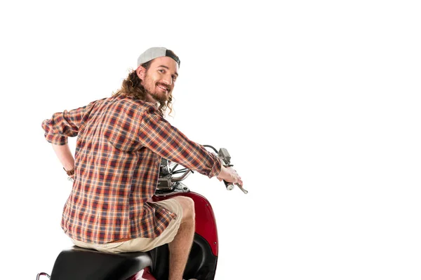 Jovem olhando para a câmera enquanto montava em scooter vermelho isolado no branco — Fotografia de Stock