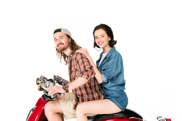 Side view of girl and young man looking at camera and smiling, sitting on red scooter isolated on white — Stock Photo