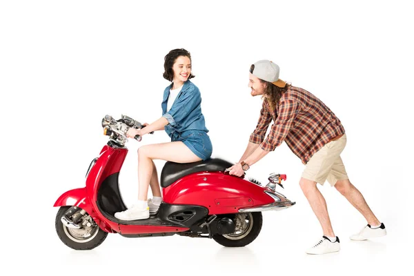 Full length view of young man pushing red scooter with girl on it isolated on white — Stock Photo