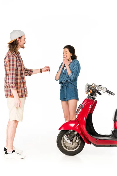 Full length view of young man giving keys from red scooter to girl isolated on white — Stock Photo