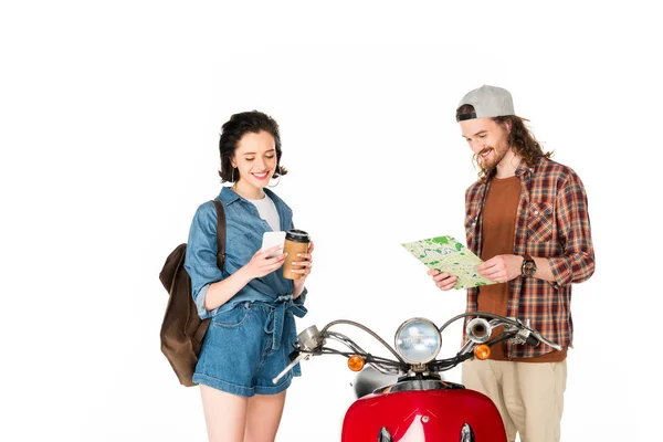 Girl looking at smartphone and holding paper cup of coffee and young man looking at map, satnding near red scooter isolated on white — Stock Photo