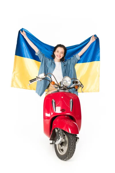 Vue pleine longueur de la fille assise sur scooter rouge et tenant drapeau Ukranian isolé sur blanc — Photo de stock
