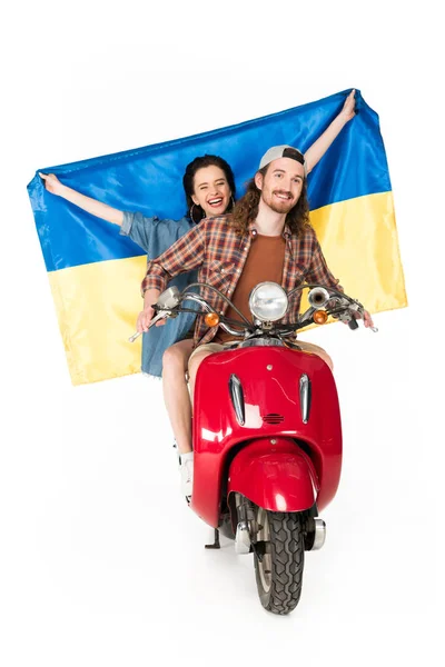 Vista completa de la muchacha sentada en scooter rojo y sosteniendo la bandera de Ukranian y el hombre joven mirando hacia adelante aislado en blanco - foto de stock
