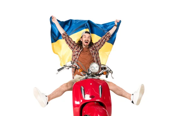 Piena vista lunghezza di felice giovane seduto su scooter rosso, tenendo bandiera ucraina in aria isolata su bianco — Foto stock
