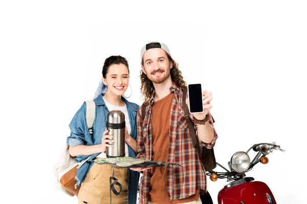 Couple de jeunes touristes debout près de scooter rouge, tenant carte, smartphone et thermos isolés sur blanc — Photo de stock