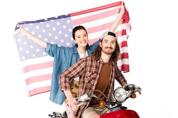 Menina bonita e jovem sentado em scooter vermelho e segurando bandeira americana isolada no branco — Fotografia de Stock