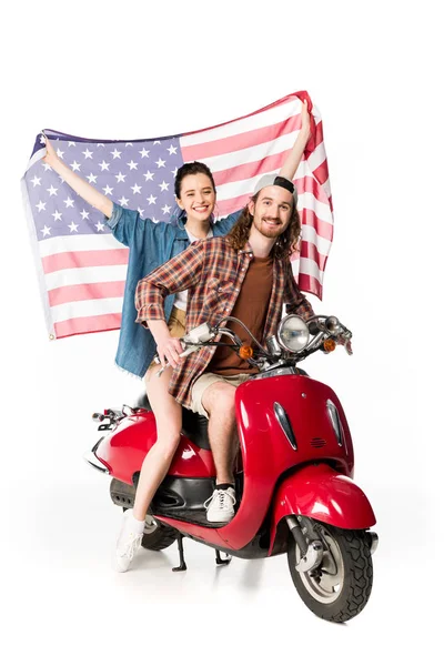 Вид в полный рост красивой девушки и молодого человека, сидящих на красном скутере и держащих американский флаг, изолированный на белом — стоковое фото