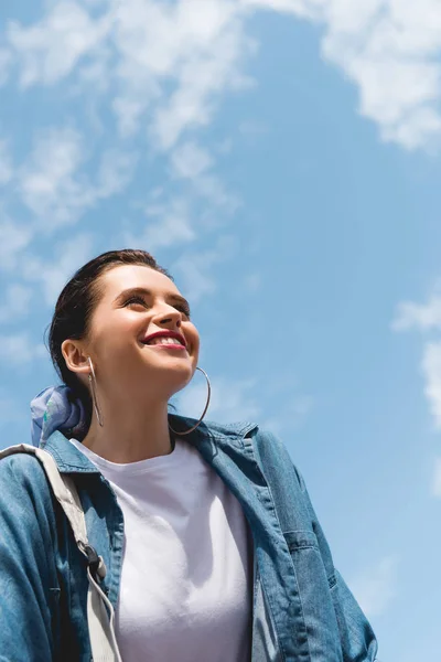 Baixo ângulo vista da menina bonita olhando para a frente e sorrindo no céu backgroung — Fotografia de Stock