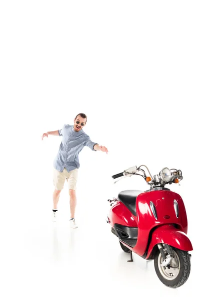 Красивий стильний молодий чоловік намагається схопити червоного скутера ізольовано на білому — стокове фото