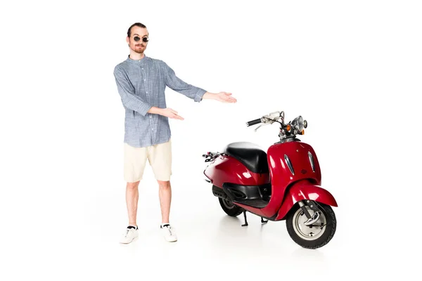Guapo elegante, impactado joven mostrando en scooter rojo aislado en blanco - foto de stock