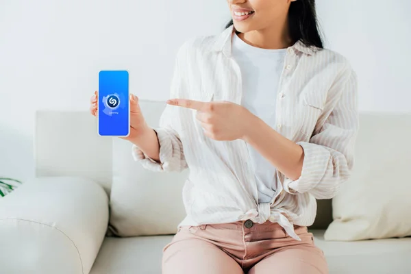 KYIV, UKRAINE - APRIL 26, 2019: Partial view of latin woman pointing with finger at smartphone with Shazam app on screen. — Stock Photo