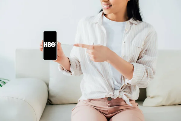 KYIV, UKRAINE - APRIL 26, 2019: Partial view of latin woman pointing with finger at smartphone with HBO app on screen. — Stock Photo