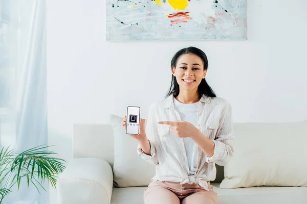 KYIV, UKRAINE - APRIL 26, 2019: Smiling latin woman showing smartphone with Uber app on screen. — Stock Photo