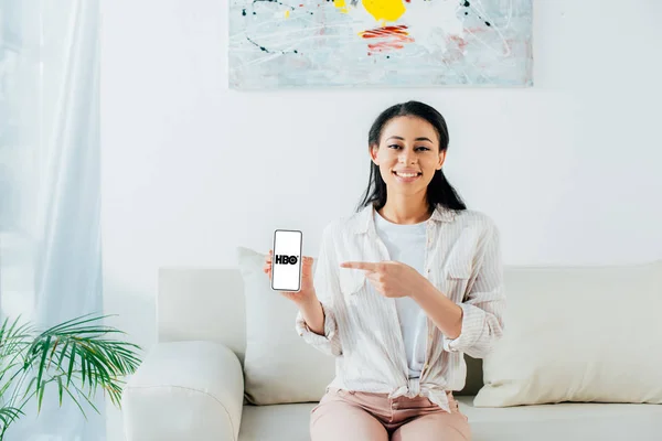 KYIV, UKRAINE - APRIL 26, 2019: Smiling latin woman showing smartphone with HBO app on screen. — Stock Photo