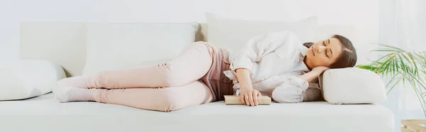 Panoramaaufnahme der schönen lateinischen Frau, die mit Buch auf der heimischen Couch schläft — Stockfoto