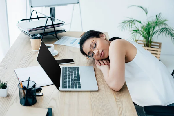 Tired latin businesswoman sleeping at workplace near notebook with blank screen — Stock Photo