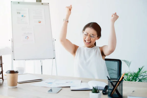 Aufgeregte Geschäftsfrau feiert Triumph, während sie am Arbeitsplatz im Büro sitzt — Stockfoto