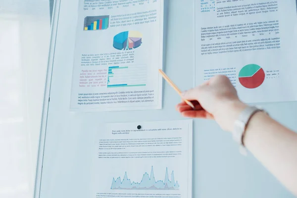 Plan recadré de femme d'affaires pointant vers le tableau à feuilles avec infographies — Photo de stock