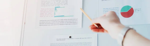 Panoramic shot of businesswoman pointing at flipchart with graphs and charts — Stock Photo