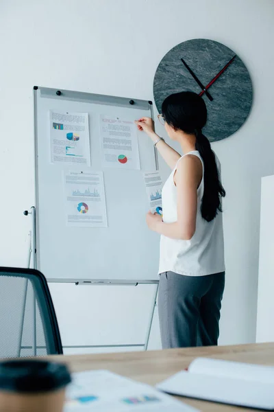 Jeune femme d'affaires latine organiser des infographies sur tableau à feuilles mobiles dans le bureau — Photo de stock