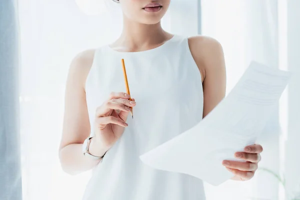 Обрезанный снимок молодой латинской предпринимательницы, смотрящей на документ и держащей карандаш — стоковое фото