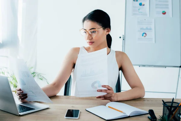 Attenta donna d'affari latina che fa scartoffie mentre è seduta alla scrivania in ufficio — Foto stock