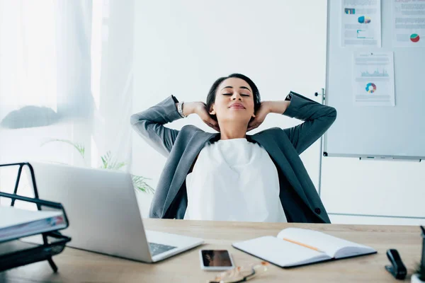 Cansado latino hombre de negocios relajarse mientras está sentado en el lugar de trabajo en la oficina - foto de stock