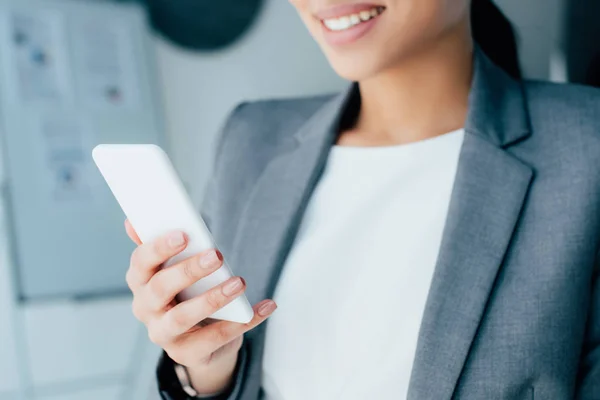 Ritagliato colpo di donna d'affari latina sorridente utilizzando smartphone in ufficio — Foto stock