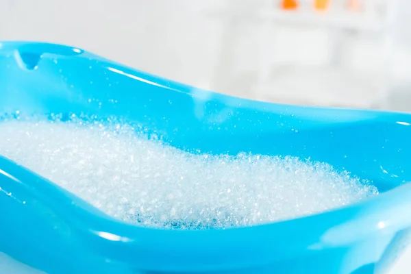 Foco seletivo da banheira de bebê azul com água e espuma de banho — Fotografia de Stock