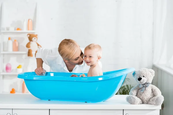 Blonde gaie mère près heureux tout-petit fils prenant bain — Photo de stock