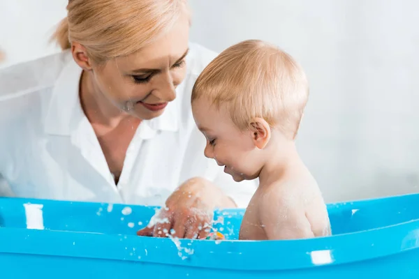 Selective focus of happy toddler kid near blonde mother in bathroom — Stock Photo