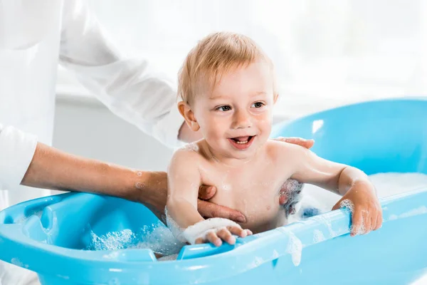 Recortado vista de la madre cerca lindo niño en el baño - foto de stock