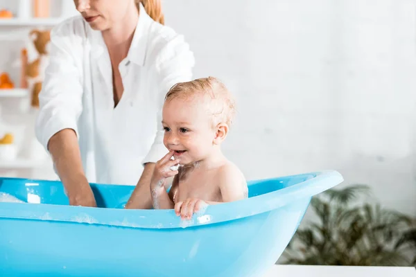 Вибірковий фокус милий малюк біля блондинки мати у ванній кімнаті — стокове фото