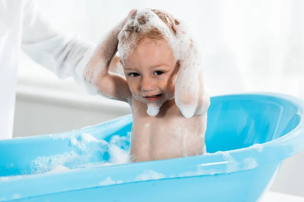 Cropped view of mother near cute toddler son washing head in bathroom — Stock Photo