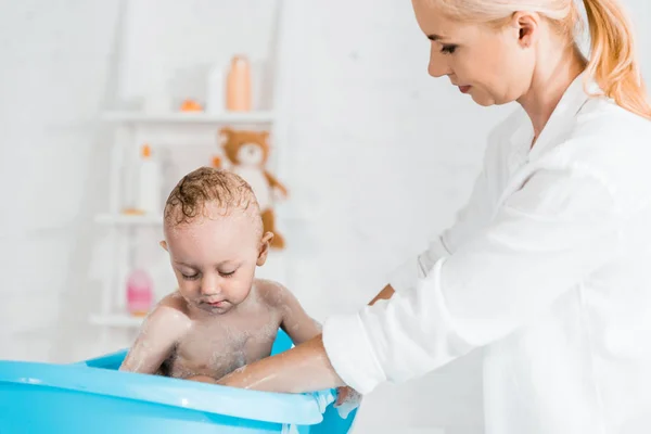 Attractive blonde mother near wet toddler son in bathroom — Stock Photo