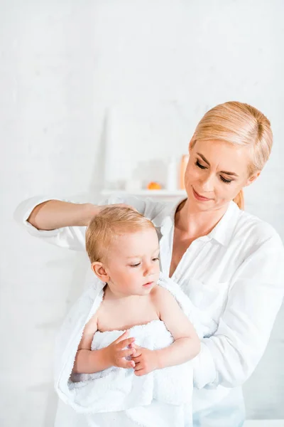 Atraente loira mãe segurando em braços criança filho no banheiro — Fotografia de Stock