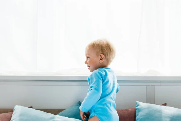 Cheerful toddler kid standing and smiling in bedroom — Stock Photo