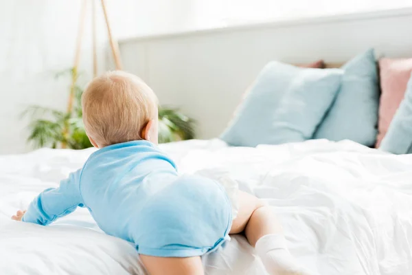Вид ззаду малюка, який плаче на ліжку в сучасній спальні — стокове фото