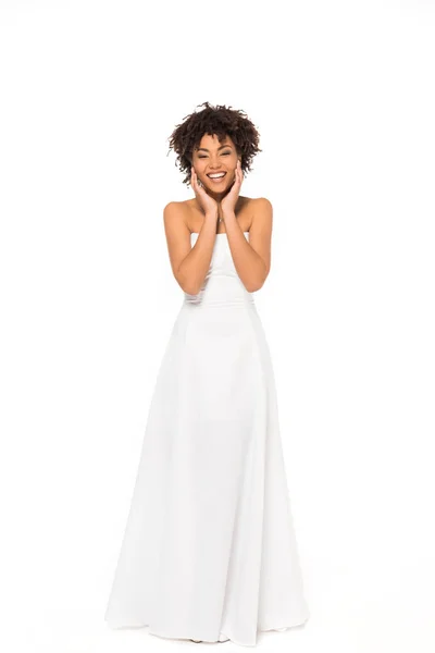 Glückliche afrikanisch-amerikanische Braut lächelt, während sie im Hochzeitskleid isoliert auf weiß steht — Stockfoto