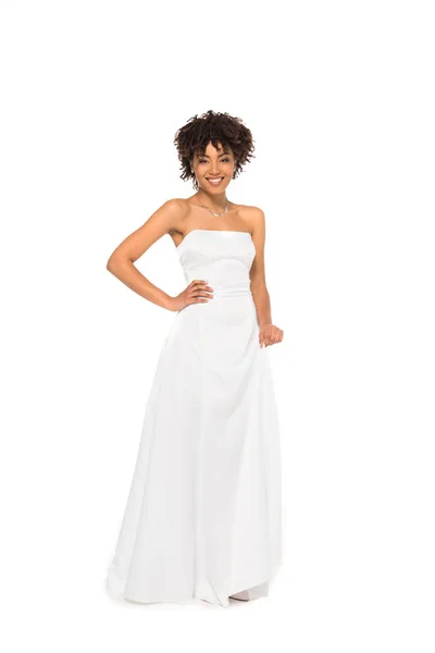 Attractive and curly african american bride standing in wedding dress with hand on hip isolated on white — Stock Photo