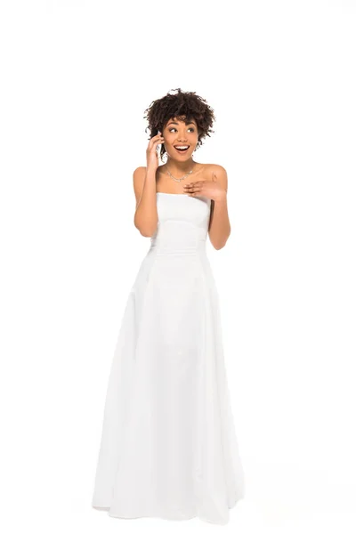 Excited african american bride standing and talking on smartphone isolated on white — Stock Photo