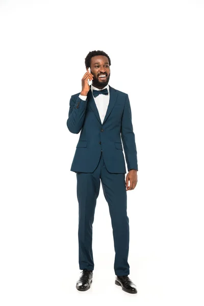 Щасливий афроамериканський наречений говорить на смартфоні і стоїть ізольовано на білому — стокове фото