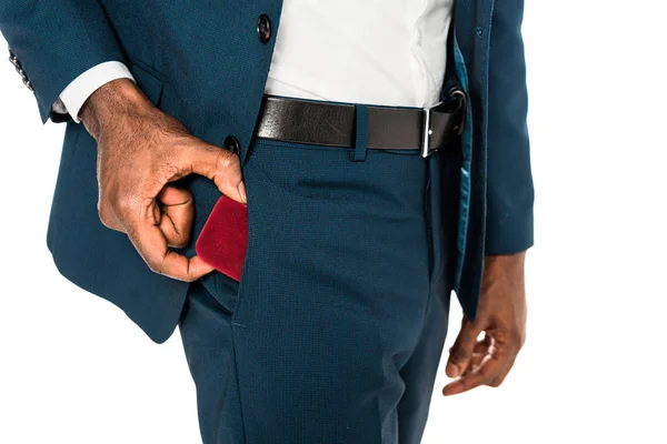 Vista ritagliata di uomo afroamericano mettendo scatola rossa in tasca isolato su bianco — Foto stock