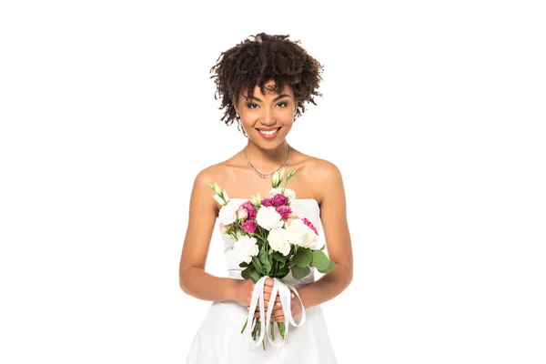 Heureuse mariée afro-américaine tenant bouquet et regardant la caméra isolée sur blanc — Photo de stock