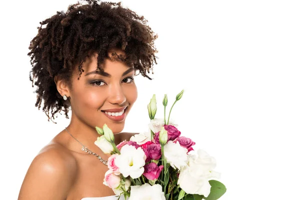 Heureux afro-américaine fille en robe de mariée tenant bouquet et regardant caméra isolé sur blanc — Photo de stock