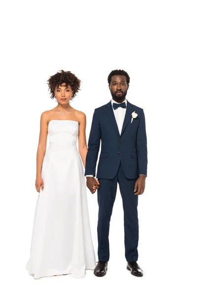 Attractive african american bride and handsome bridegroom holding hands while standing isolated on white — Stock Photo