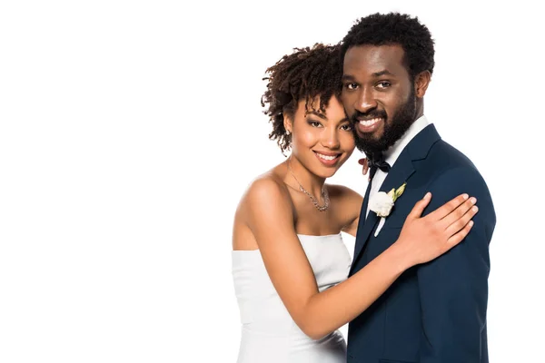 Joyeux marié afro-américain et mariée étreignant et regardant la caméra isolée sur blanc — Photo de stock