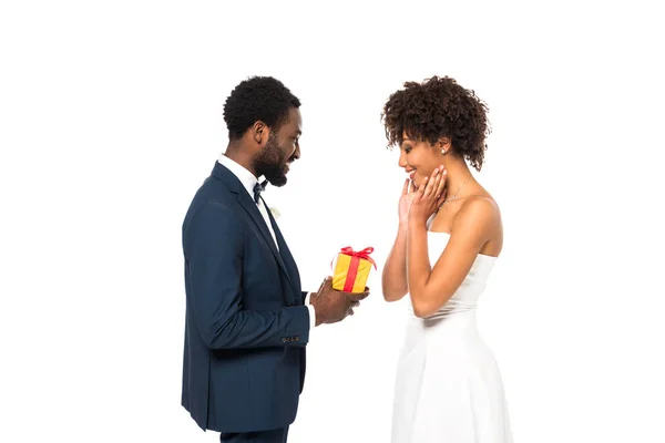 Heureux marié afro-américain donnant cadeau à la mariée gaie isolé sur blanc — Photo de stock