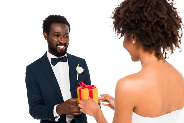 Messa a fuoco selettiva di felice sposo afro-americano dando regalo alla sposa riccia isolata su bianco — Foto stock